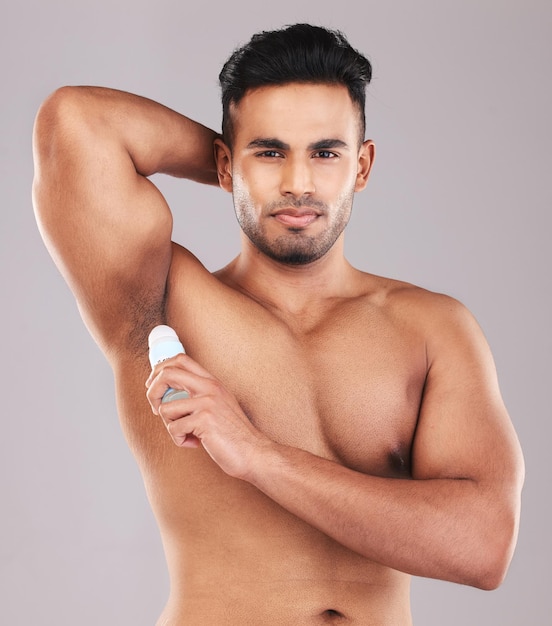 Deodorant health and man cleaning armpit against a grey studio background Wellness care and portrait of a young model with an underarm product for grooming clean skin and care for body hygiene