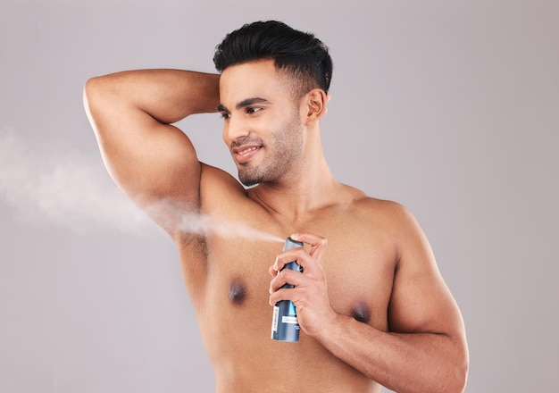 Deodorant oksel en man spuiten in studio voor hygiëne, wellness en zelfzorg Spray schoon en jong model uit Colombia met geur met een frisse geur voor verzorging geïsoleerd door grijze achtergrond