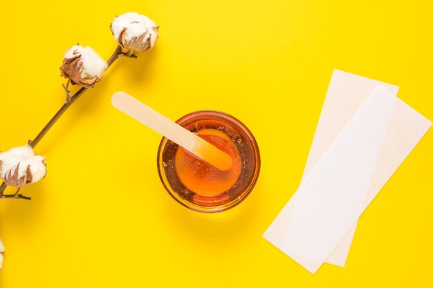 depilatory sugar paste with a wooden spatula on a yellow background epilation depilation