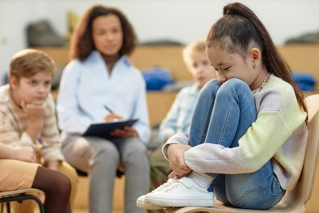 Depressed asian girl in support group meeting for children