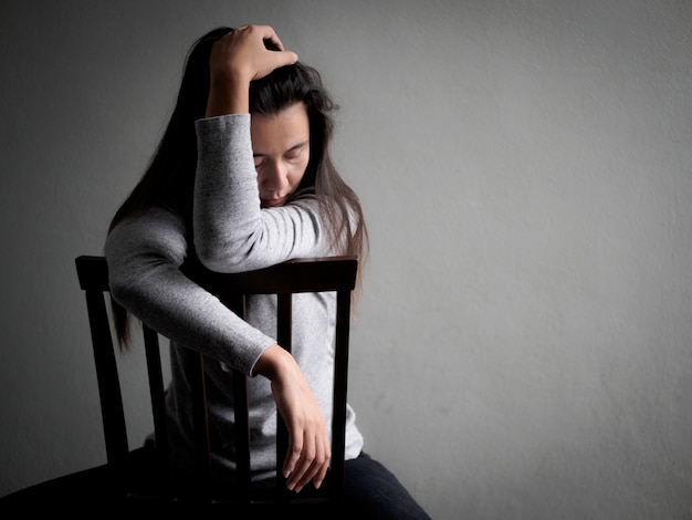 depressed broken hearted woman sitting alone on a wooden chair.