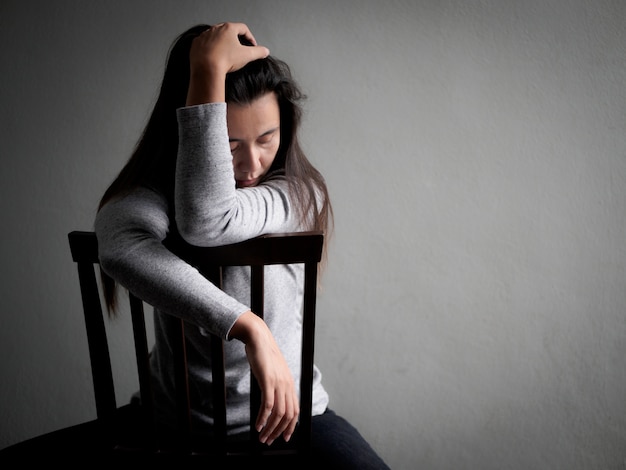 Photo depressed broken hearted woman sitting alone on a wooden chair.