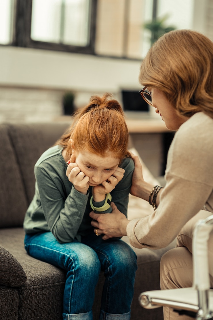 Photo depressed child. sad red haired girl holding her cheeks while feeling depressed