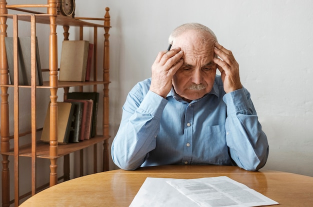 Uomo anziano depresso e preoccupato che fa le scartoffie