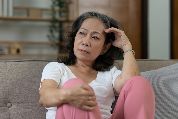 写真 落ち込んでいる年配のアジア人女性が一人で家に座っている退職した女性のコンセプト