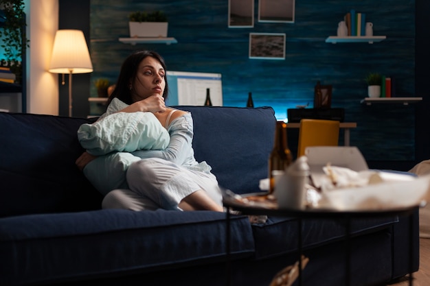 Depressed, frustrated, stressed, traumatised woman sitting alone holding pillow feeling emotionally vulnerable, lonely desperate, scared suffering from break up having anxiety, mental health problems