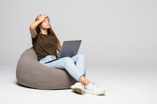 Depressed and frustrated woman working with computer laptop desperate in work isolated on white wall . Depression.