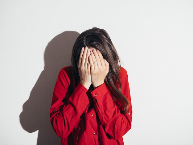 Photo depressed girl in a red shirt against the wall