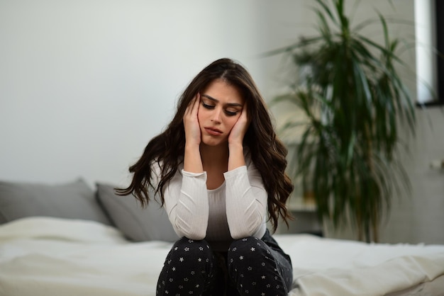 Photo depressed girl sitting on the bad