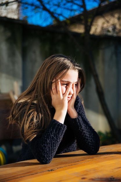 Photo depressed girl with head in hands sitting at backyard