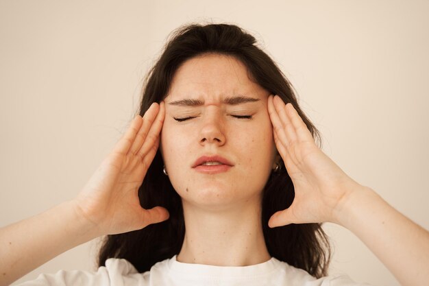 Depressed girl with migraine headache sad woman touches temples\
because of stress and despair in her life problems in life