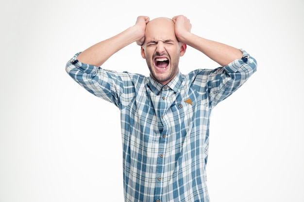 Depressed hysterical young man in checkered shirt screaming loudly over white wall