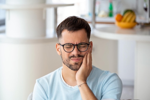 写真 歯痛を持ち、頬に触れる意気消沈した病気の男性 歯の痛みの齲蝕に苦しむ若い男 歯痛のクローズアップに苦しむ男性の肖像画