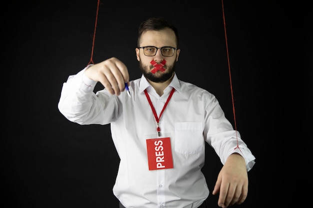 Depressed journalist holds hands tied with ropes like marionette wrapping mouth