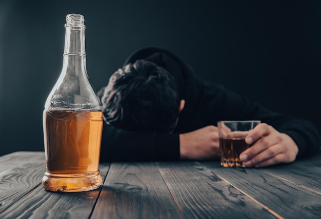 Depressed man drinking alcohol indoors