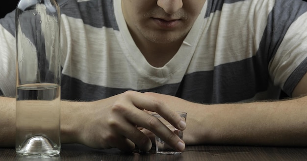 depressed man drinking vodka alone in a dark room concept of alcoholism