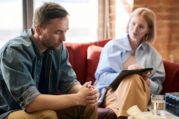 Depressed man having consultation with psychologist he sitting on sofa and talking about his problem