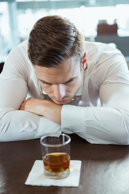 Depressed man looking at alcohol glass