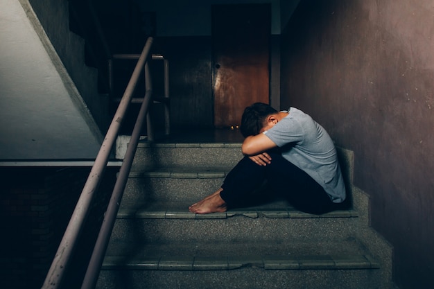 Depressed man.Sad man sitting hugging their knees on the stairs in building