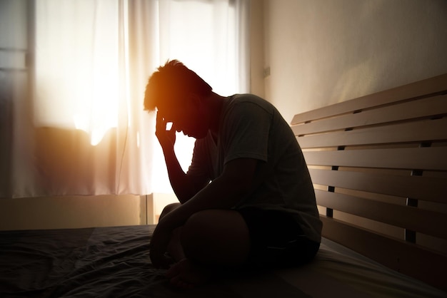 家のベッドに座っているうつ病の男性