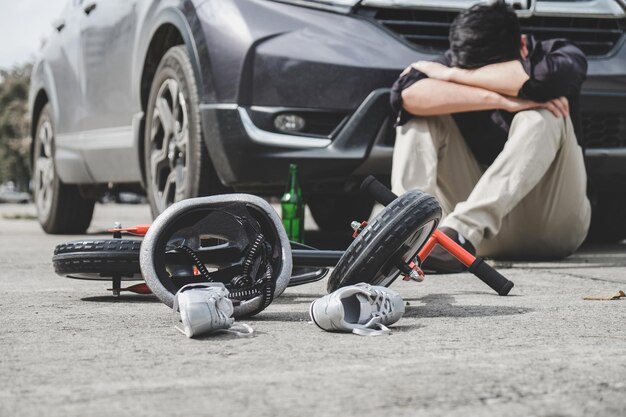 Photo depressed man sitting by bicycle and car on road during accident