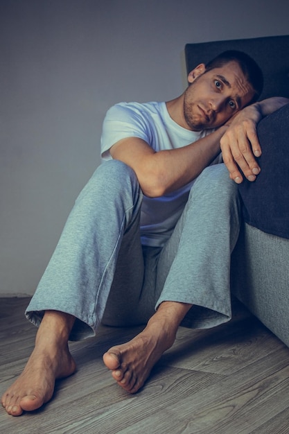 Depressed man sitting on the floor with his head down and leaning against the wall In frustrated feelings The concept of mental disorders Schizophrenia psychosis fear