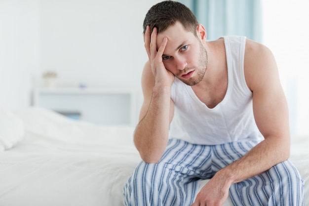 Depressed man sitting on his bed