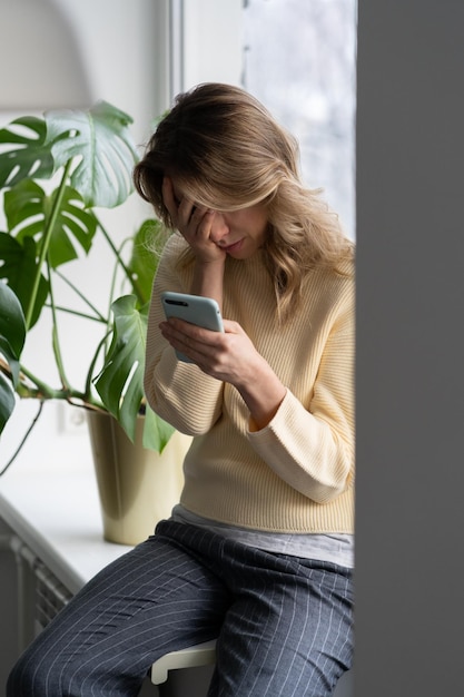 Depressed middle age woman crying holds smart phone read unpleasant sms receiving bad news at home