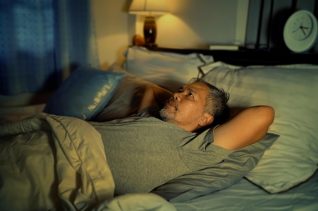 Photo depressed old man and stressed lying in bed from insomnia