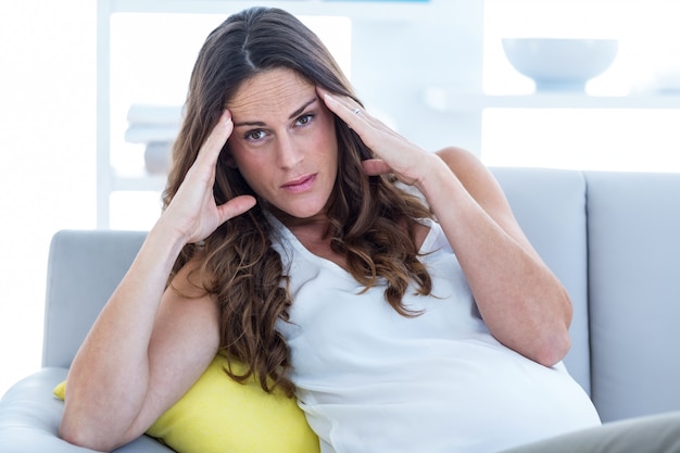 Depressed pregnant woman sitting in living room
