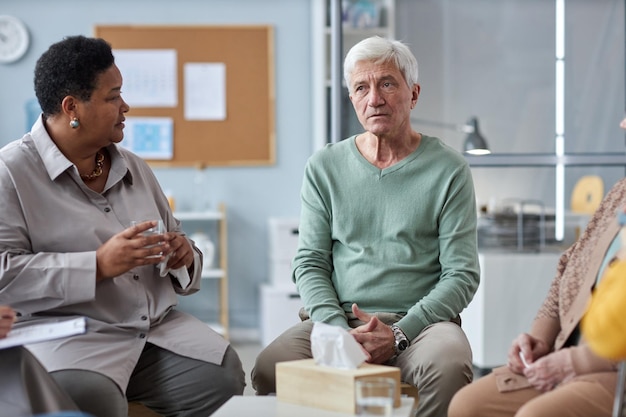 Depressed senior man speaking in mental health support group