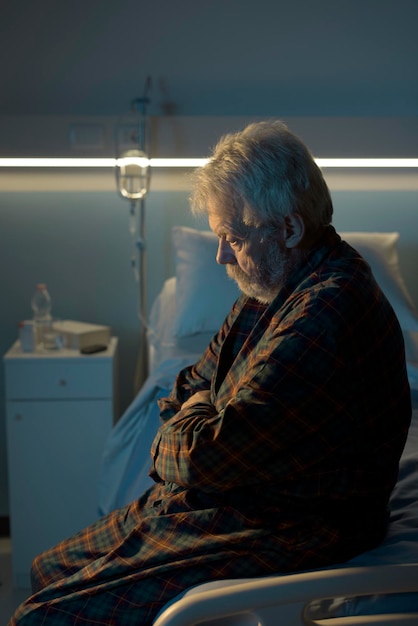 Photo depressed senior sitting on the hospital bed alone