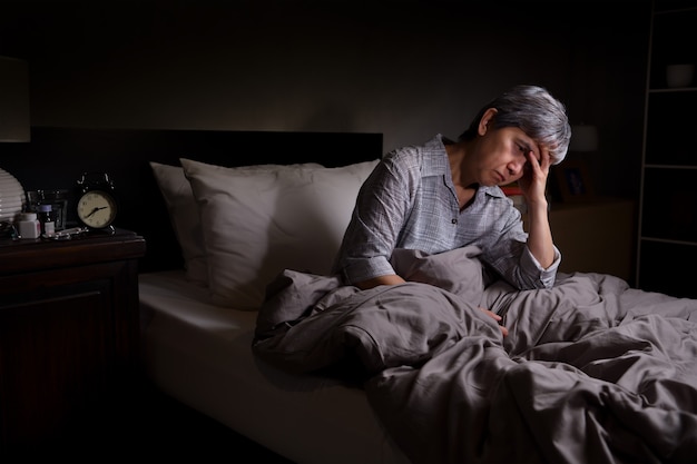 Photo depressed senior woman sitting in bed cannot sleep from insomnia