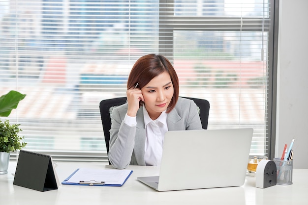 Depressed stressed young Asian business woman with laptop suffering from trouble