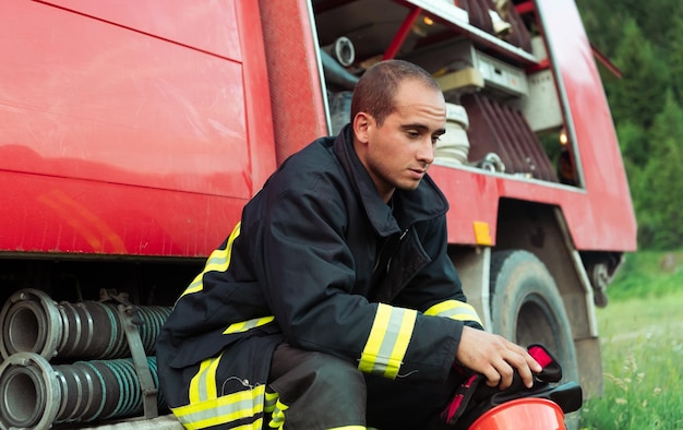 depressed and tired firefighter near fire truck. High quality photo