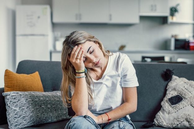 depressed or tired teen girl feeling stress headache hurt pain sitting alone at home upset sad heartbroken young woman regret pregnancy or abortion troubled with problem or psychological trauma