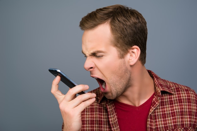 Depressed tired young man screaming on his mobile phone