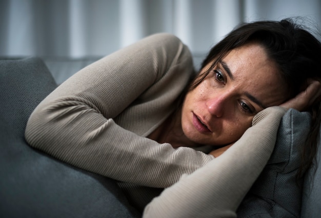 Depressed woman laying down on sofa