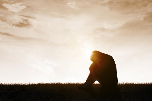 Depressed woman sitting on the meadow