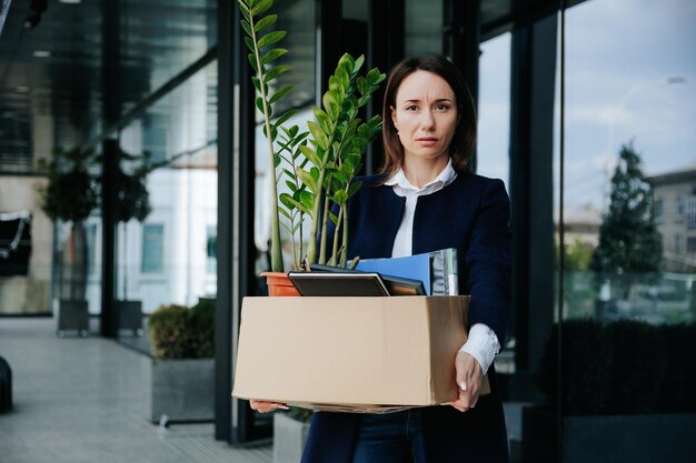 Foto una donna depressa seduta fuori circondata da scatole di cartone ritrae la profonda tristezza e disperazione derivanti dalla perdita del lavoro il fardello della perdita del lavoro donna stressata che afferra una scatola di cartone