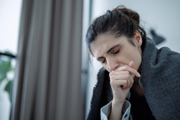 家で情緒的な痛みを感じる毛布に包まれたうつ病の女性