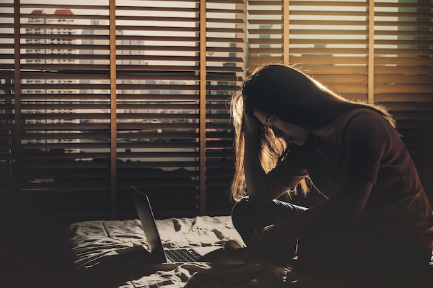 Photo depressed women sitting head in hands when working with technology laptop