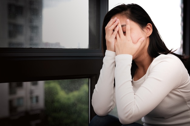 Depressed women sitting near window, alone, sadness, emotional concept