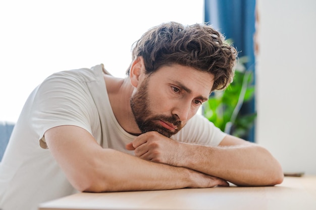 depressed young bearded man at home lying on the table