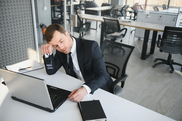 Depressed young businessman holding head in hands has problem a laptop on the desk A guy made a mistake in a work