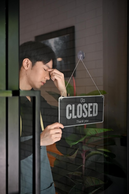 Depressed young coffee shop owner closing his coffee shop