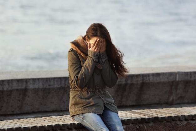 写真 ベンチに座って意気消沈した若い女性