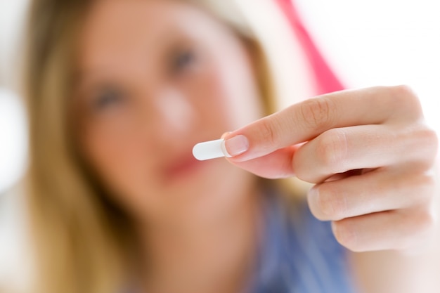 Depressed young woman taking pills at home.