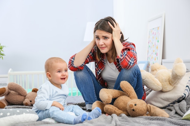 Depressed young woman with cute baby at home