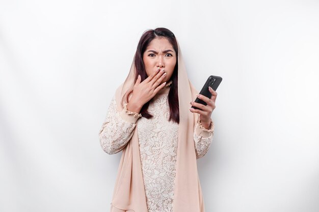 A depresses Asian Muslim woman wearing a headscarf looks stressed while talking on the phone isolated by white background